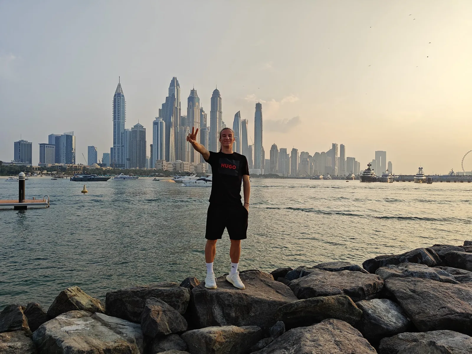 Ivan Vojvoda stoji na stijenama uz more s panoramom nebodera Dubaija u pozadini